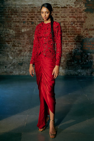 Three-quarter view of the red jacket's full sleeves over the draped skirt with its slit by Asaga at Mrs. G
