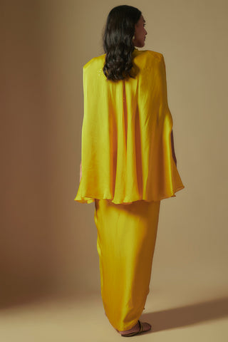 Back view of yellow short cape with structured shoulders over a draped satin skirt by Asaga at Mrs. G