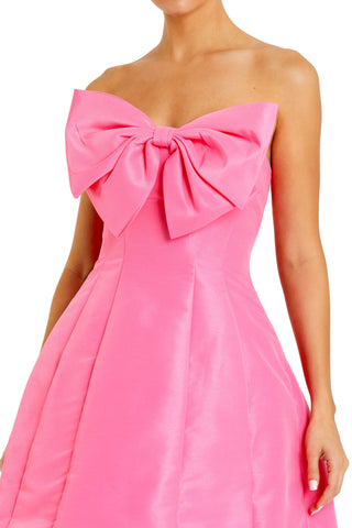 Close-up of the oversized bow at the strapless neckline and structured taffeta skirt panels in pink by Mac Duggal at Mrs. G