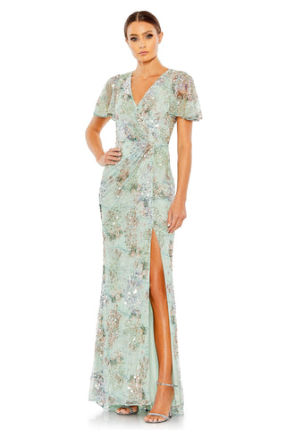 Full-length three-quarter view of the green sequin faux wrap gown with a thigh-high slit by Mac Duggal at Mrs. G