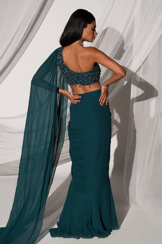 Back view of the teal lehenga set showing the one-shoulder back, veil sleeve and flared hem by Kiyohra at Mrs. G