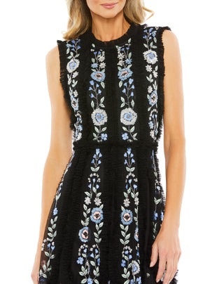 Close-up of the blue and white floral embroidery and ruffled neckline on the black sleeveless dress by Mac Duggal at Mrs. G