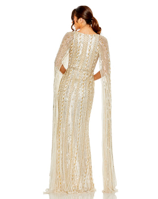 Back view of the champagne silver cape sleeve gown with a closed back and floor-length skirt by Mac Duggal at Mrs. G