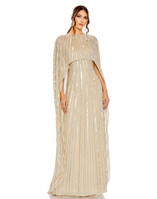 Full-length front view of the champagne column gown with a sheer beaded cape overlay and boat neckline by Mac Duggal at Mrs. G
