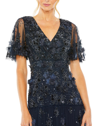 Close-up of the V-neckline, sheer flutter sleeves and 3D flowers on the midnight beaded bodice by Mac Duggal at Mrs. G