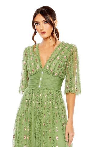 Waist-up view of the moss green floral ruffle empire waist gown showing the ruffled V neckline and three jeweled buttons by Mac Duggal at Mrs. G