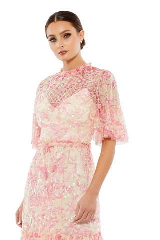 Waist-up view of the blush multi floral sequin flounce sleeve short dress showing the ruffled high neckline and sheer flounce sleeves by Mac Duggal at Mrs. G