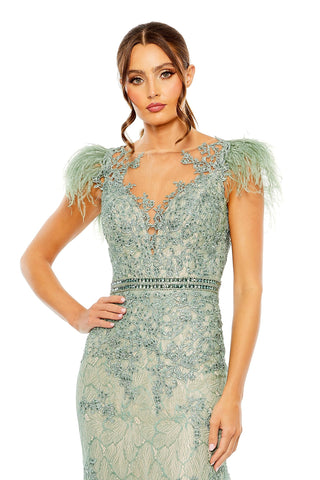 Waist-up view of the sage embellished feather cap sleeve illusion trumpet gown showing the feather cap sleeves and illusion neckline by Mac Duggal at Mrs. G