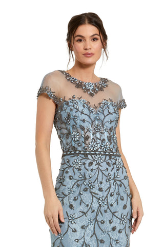 Waist-up view of the slate blue sheer top embellished mermaid gown showing the beaded floral illusion neckline and short sleeves by Mac Duggal at Mrs. G