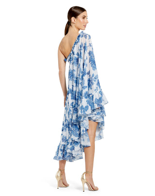 Back three-quarter view of the white multi dress showing the flowing sleeve and ruffled asymmetrical hem by Mac Duggal at Mrs. G