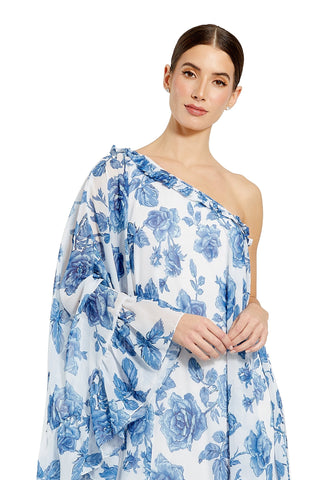 Waist-up view of the white multi rose print chiffon one shoulder cape sleeve dress showing the ruffled one shoulder neckline and blue rose print by Mac Duggal at Mrs. G