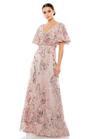 Three-quarter front view of the rose pink floral gown with faux wrap V-neck and flutter sleeves by Mac Duggal at Mrs. G