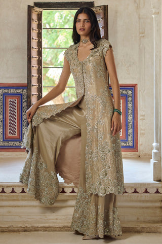 Seated view of beige champagne jacket open at the front over flared pants with floral hem by Osaa by Adarsh at Mrs. G