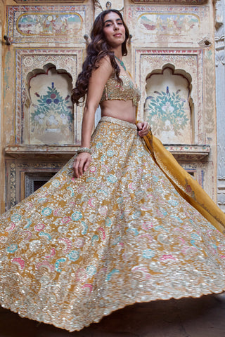 Side view of honey orange lehenga in motion with turquoise and pink flower appliqué by Osaa by Adarsh at Mrs. G