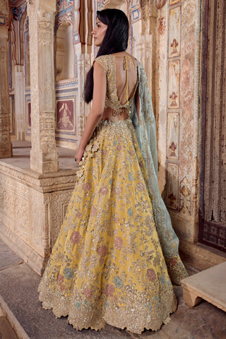 Back three-quarter view of the maize yellow lehenga with deep scooped back and floral embroidered flare by Osaa by Adarsh at Mrs. G
