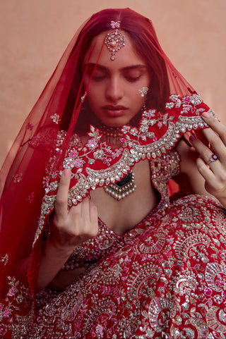 Seated view of rosewood red bridal lehenga with sheer veil over the head and scalloped dupatta by Osaa by Adarsh at Mrs. G