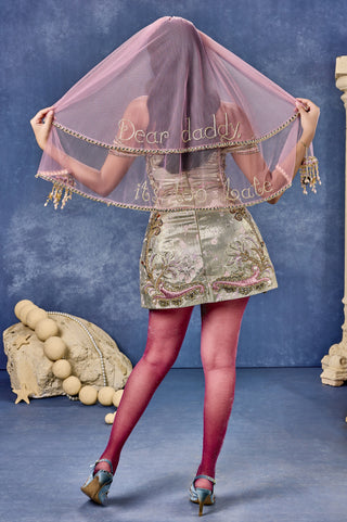 Back view of the sage green babydoll dress with the veil and embroidered skirt panels at Mrs. G