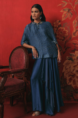 Front view with a hand on the chair back and the top worn loose, blue ziya mirrorwork skirt set by Twenty Nine at Mrs. G