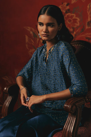 Seated view of the top and skirt in a carved wooden chair, blue ziya mirrorwork skirt set by Twenty Nine at Mrs. G