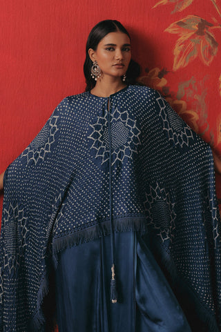 Seated view of the cape with a tassel fringe against a red backdrop, blue ziya tassel cape with dhoti by Twenty Nine at Mrs. G